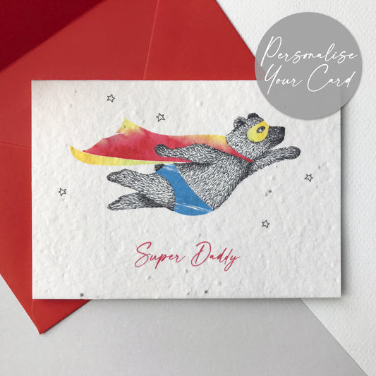 Bloom Cards plantable seed paper Super Daddy card with black and white pen illustration of a flying super bear wearing a red and yellow cape and blue underpants. There are small outline stars around him and the text underneath is red and reads Super Daddy. The card is printed onto recycled paper embedded with wildflower seeds. The card is blank inside, has planting instructions printed on the back and comes with a recycled red envelope. Illustrated and printed in Lancashire by Suzanne Marie Paperie.