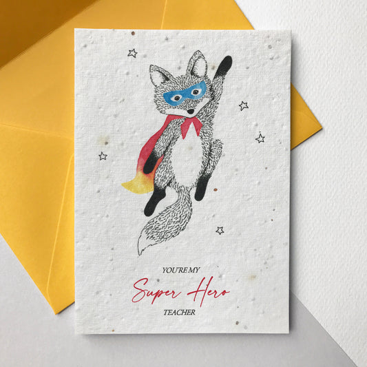 Photo of a Super Hero Teacher plantable wildflower seed card in yellow. The card has a pen and watercolour flying superhero fox wearing a cape and mask. Text reads Youre my Super Hero Teacher. The card comes with a yellow eucalyptus paper envelope.