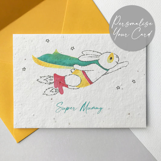 A photo of a hand illustrated Super Mummy plantable wildflower seed card in yellow. A pen drawn bunny is flying through the stars wearing a watercolour painted turquoise and yellow cape, yellow mask and pants, red belt and red rocket boots. The turquoise personalised text underneath reads Super Mummy. The card comes with a yellow fsc certified eucalyptus paper envelope.