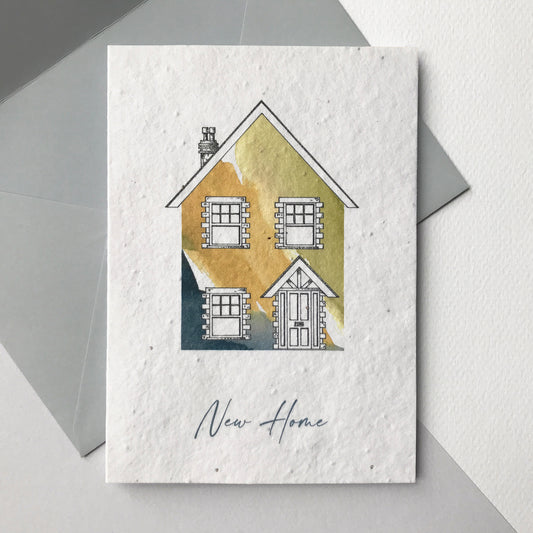 Image of a Bloom Cards A6 plantable new home card featuring a hand illustrated house design. Watercolour washes in grey, natural and green are used to create a colourful house, with pen drawn details. The grey text underneath reads 'New Home'. This recycled cotton card is printed onto wildflower seed paper, so your recipient can grow their card and enjoy beautiful flowers in their new home. The card comes with a matching grey coloured fsc certified eucalyptus envelope.