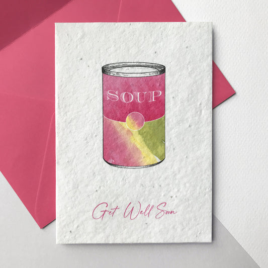 Image of a Bloom Cards A6 plantable get well soon card featuring a colourful hand illustrated soup tin design. Washes of magenta, green and yellow watercolour make a colourful tin with pen drawn details and the word 'Soup' on the front. The pink text underneath reads 'Get Well Soon'. Printed onto eco-friendly paper made from recycled cotton and embedded with wildflower seeds. The card comes with a matching magenta pink fsc certified eucalyptus envelope.