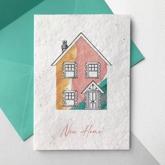 Image of a Bloom Cards A6 plantable new home card featuring a hand illustrated house design. Watercolour washes in coral, mint and yellow are used to create a colourful house, with pen drawn details. The pink text underneath reads 'New Home'. This recycled cotton card is printed onto wildflower seed paper, so your recipient can grow their card and enjoy some beautiful flowers in their new garden. The card comes with a matching mint green fsc certified eucalyptus envelope. Handmade by Suzanne Marie Paperie.