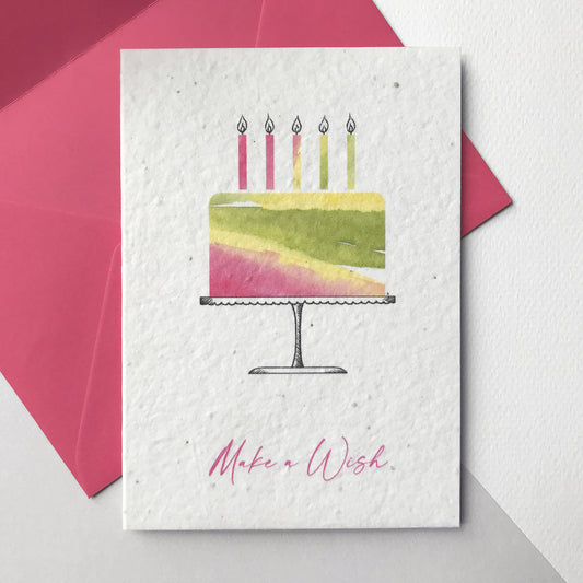 This A6 Bloom Cards plantable birthday card features a hand illustrated watercolour and pen illustration of a cake and candles in washes of pink, yellow and green. The magenta pink text underneath reads 'Make a Wish'. The card is blank inside and comes with a magenta pink fsc certified eucalyptus paper envelope. Plant this cards and grow a beautiful mix of bee friendly wildflowers for the garden or patio.