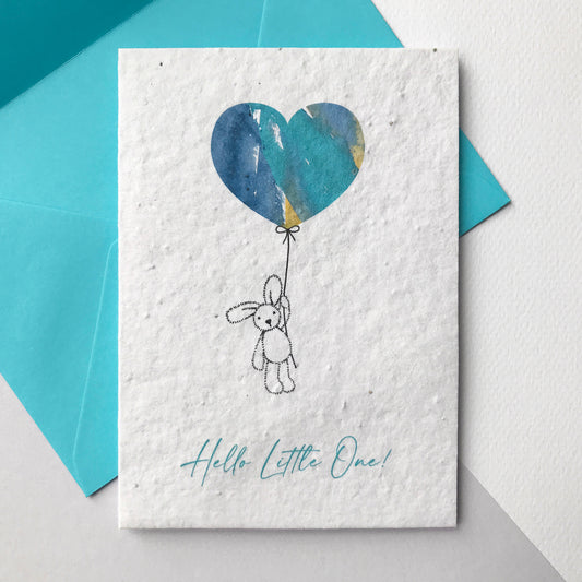Image of a Bloom Cards A6 plantable New Baby card featuring a cute hand illustrated bunny and balloon design. A pen drawn bunny holds a turquoise, blue and orange watercolour heart shape balloon. The blue text underneath reads 'Hello Little One!'. Printed onto eco-friendly paper made from recycled cotton and embedded with wildflower seeds. The card comes with a matching blue fsc certified eucalyptus envelope. Made by Suzanne Marie Paperie.
