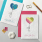 Image shows two A6 Bloom Cards plantable New Baby cards in blue and magenta. The cards feature a hand illustrated watercolour and pen bunny and heart shape balloon design. The text underneath reads 'Hello Little One!'. Printed onto recycled cotton paper and embedded with wildflower seeds. Easy to grow and a great activity for parents and older siblings to enjoy together. Each card is blank inside and comes with matching fsc certified eucalyptus paper envelope.